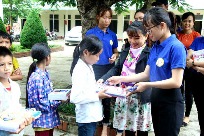 Các tình nguyện viên trao tặng vở viết và bút cho các học sinh nghèo của trường tiểu học Quang Phong 1. Ảnh: Hùng Cường