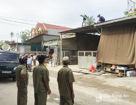 Các lực lượng tham gia giải tỏa cắt mái tôn lấn chiếm hành lang an toàn giao thông ở phường Quỳnh Phương. Ảnh: Nguyễn Vân