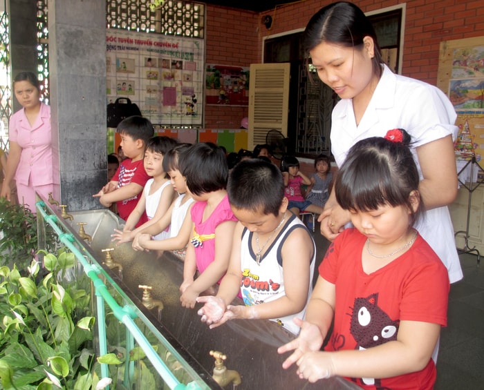 Cán bộ y tế hướng dẫn học sinh mầm non Hưng Phúc (TP.Vinh) rửa tay với xà phòng. Ảnh: Nguyệt Minh