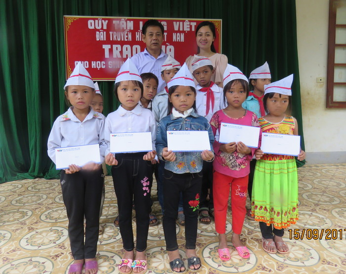 Đại diện Quỹ tấm lòng Việt - Đài Truyền hình Việt Nam và lãnh đạo nhà trường trao quà cho các em có hoàn cảnh đặc biệt khó khăn