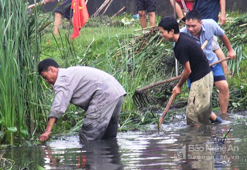 Người dân phát quang cỏ dại, vớt bèo rác khơi thông dòng chảy. Ảnh: Hồng Quang