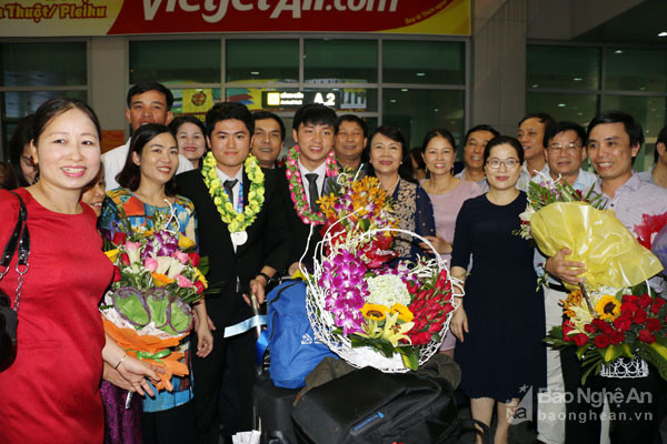 Thứ trưởng Bộ Giáo dục và Đào tạo cùng các thành viên trong đoàn tặng hoa chúc mừng các thành viên của Nghệ An chiến thắng trở về. Ảnh: Mỹ Hà