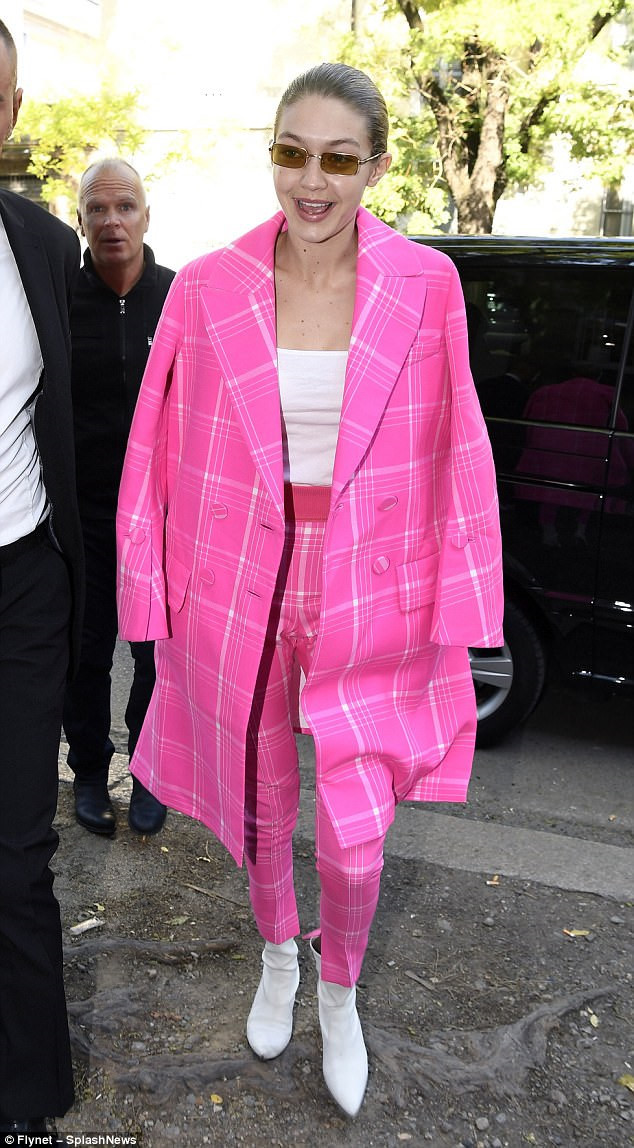 Gigi Hadid nổi bật trên phố với set đồ kẻ caro hồng nổi bật phối cùng áo thun và ankle bốt đồng màu trắng cá tính.
