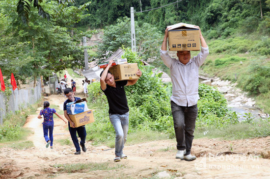 Người dân và các thành viên trong Liên quân báo chí Nghệ An đưa hàng trung thu cho các em học sinh Hữu Khuông.