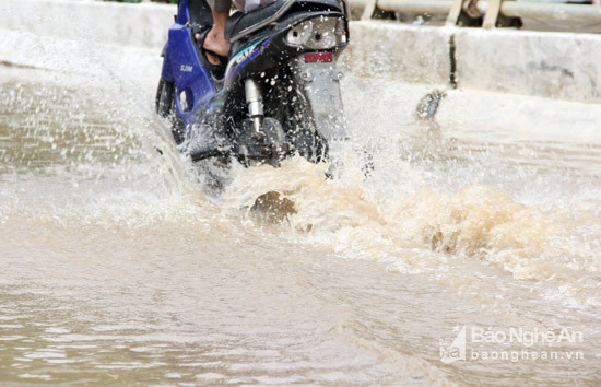 Nước ngập cao gây rất nhiều kho khăn các phương tiện tham gia giao thông qua đoạn đường này. Ảnh: Hồ Phương