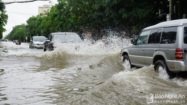 Các xe ô-tô di chuyển nhanh để tránh ngập làm sóng nước bắn tung tóe lên các phương tiện khác. Ảnh: Thành Cường.