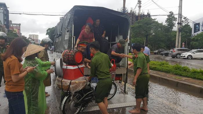 Đội cứu hộ của Công an Thành phố Vinh hỗ trợ những hộ dân buôn bán nhỏ qua tuyến đường bị ngập nước. Ảnh: Mỹ Hà