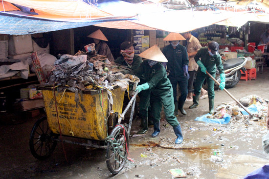 Lực lượng dọn vệ sinh gồng mình dọn rác sau mưa lớn tại chợ Vinh. Ảnh: Quang An