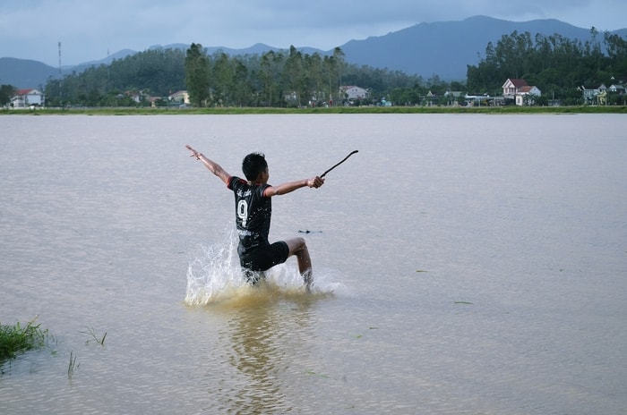 Quyết không để cho lũ chuột có cơ hội gây hại, nhiều người ào xuống nước đuổi bắt. Ảnh: Lê Khánh Thành