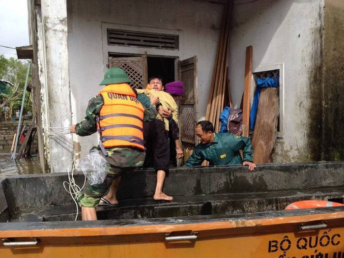 Cán bộ, chiến sỹ Ban CHQS huyện Nghi Lộc di chuyển người già, trẻ em ra khỏi vùng ngập sâu. Ảnh: Quang Dũng