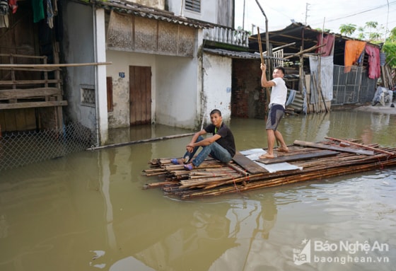 Đường bị ngập sâu, đi lại khó khăn, người dân phải kết nứa thành bè để di chuyển trên “phố”. Ảnh: Thành Cường.