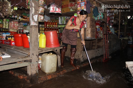 Chị Lê Thị Ninh, tiểu thương chợ Vinh liên tục khơi thông nước ngập tránh tràn vào hàng. Ảnh: Q.A