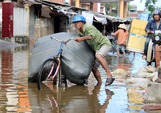 Ngay khi trời tạnh, tiểu thương hì hục đẩy hàng về vì nghe tin sắp có lũ chồng lũ và bão số sắp 11 đổ bộ. Ảnh. Q.A