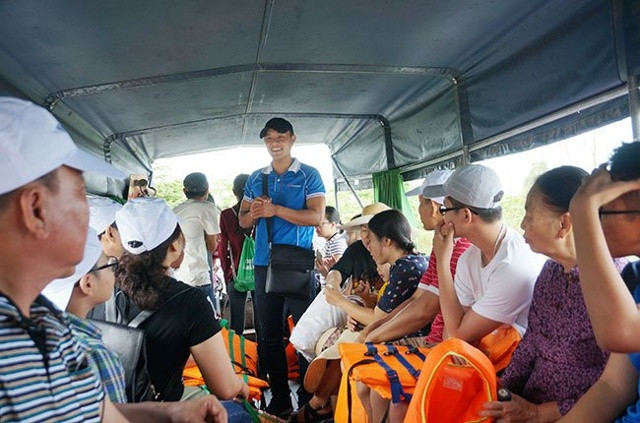 Hướng dẫn viên đang hướng dẫn du khách trên một thuyền du lịch ở Cần Thơ 