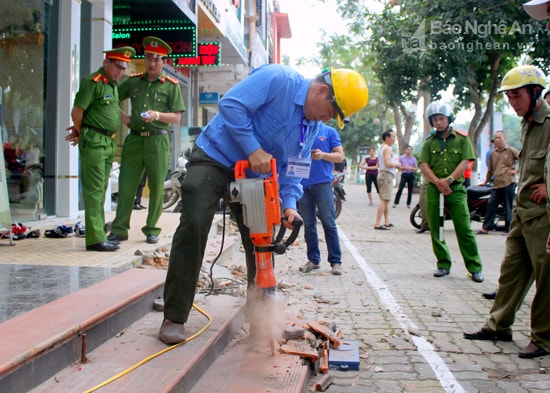 Các lực lượng chức năng tháo dỡ các tam cấp lấn chiếm hành lang vỉa hè trên đường Hồ Tùng Mậu, P.Trường Thi. Ảnh: Quang An