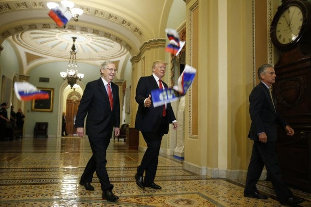 Tổng thống Donald Trump cử chỉ với các phóng viên khi lá cờ Nga bị ném ra khỏi một người biểu tình rơi xuống trước mặt Tổng thống và trưởng Mitch McConnell khi Thượng viện đến dự bữa tiệc chính thức của đảng Cộng hòa tại Đồi Capitol ở Washington, ngày 24 tháng 10 năm 2017