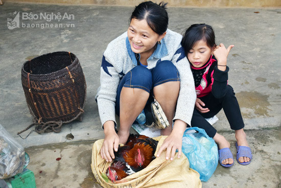  Hai mẹ con chị Xồng Thị Lý mang 2 con gà trống ra chợ Tri Lễ bán. Ảnh: Xuân Hoàng