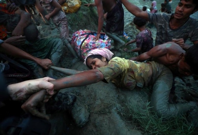 Một nhiếp ảnh gia giúp người tị nạn Rohingya đi ra khỏi sông Naf khi họ băng qua biên giới Myanmar-Bangladesh ở Palong Khali, gần Cox's Bazar, Bangladesh. Ảnh: Reuters