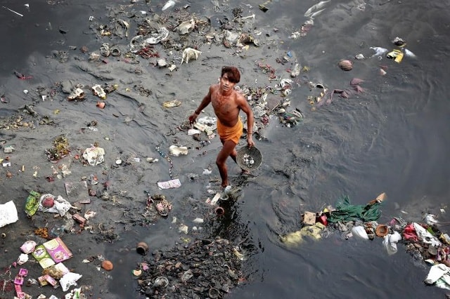Một người đàn ông đứng giữa bãi rác trên sông Yamuna ở Delhi, Ấn Độ. Ảnh: Reuters
