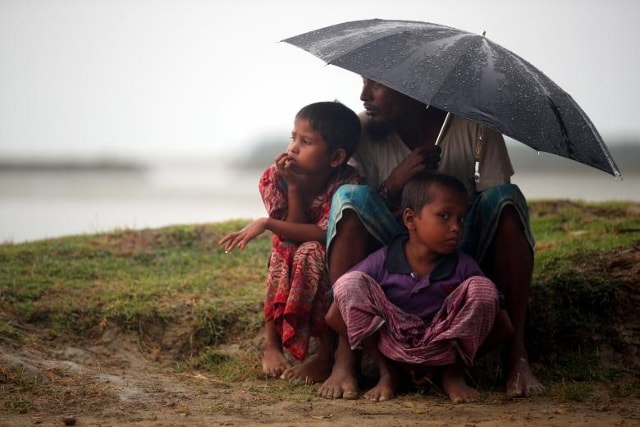 Những người tị nạn Rohingya trú ẩn từ mưa khi họ chờ đợi để được phép của quân đội Bangladesh tiếp tục hành trình sau khi vượt biên giới Bangladesh-Myanmar, tại cảng Teknaf, Bangladesh.
