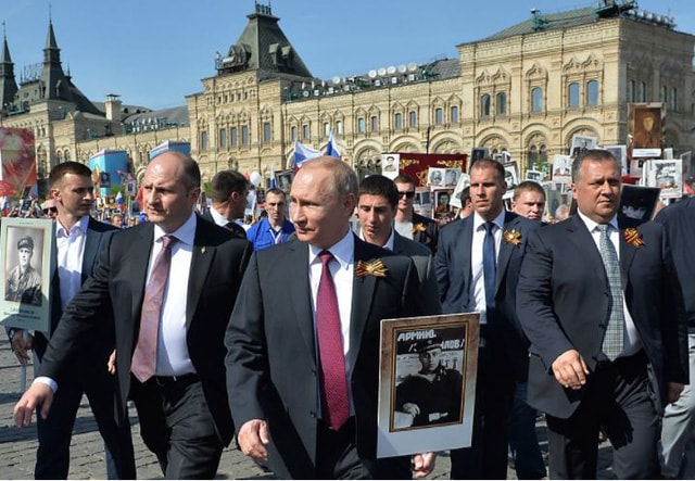 Ông Putin cầm tấm ảnh thân phụ - một cựu binh tham gia chiến tranh vệ quốc tham gia tuần hành ở Matxcơva tháng 5/2016.  Ảnh: TASS