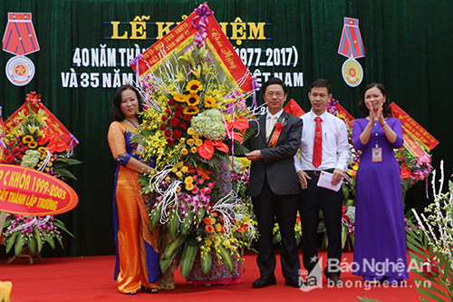 Đồng chí Nguyễn Xuân Sơn trao tặng lãng hoa tươi thắm cho tập thể thầy và trò nhà trường tại Lễ kỷ niệm. Ảnh: Hữu Hoàn