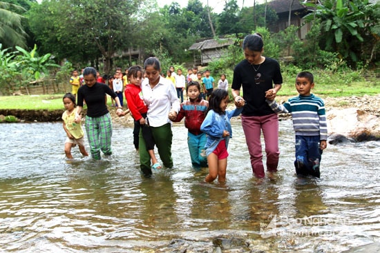 Giáo viên bản Minh Thành đón học sinh qua suối đến trường. Ảnh: Đào Thọ