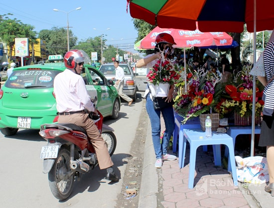 Các cửa hàng hoa ven đường cũng đã có nhiều người dừng mua. Gía các bó hoa này dao động 70.000 - 120.000 đồng tùy kích thước. Ảnh: Quang An