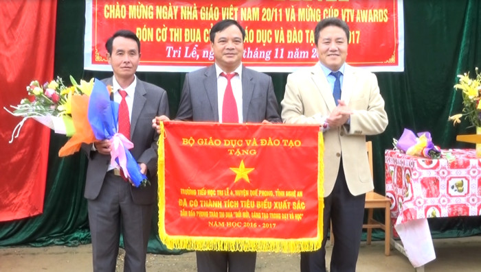 Chủ tịch UBND huyện Quế Phong Lê Văn Giáp trao cờ thi đua của Bộ giáo dục và đào tạo cho nhà trường. Ảnh: Ngọc Tăng