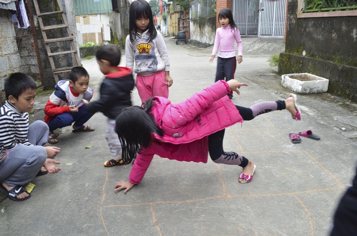 Em nhỏ này phải nhoài cả người để với chì ở khá xa với tầm tay trong khi chân vẫn phải lò cò. Ảnh: Lê Khánh Thành