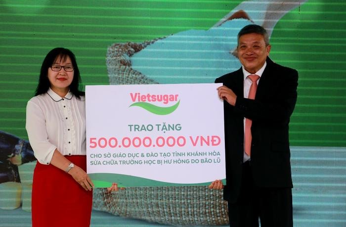 Ông Đỗ Thành Liêm - Tổng Giám đốc Công ty Cổ phần Đường Việt Nam đại diện trao bảng tượng trưng phần quà 500 triệu đồng cho Bà Hoàng Thị Lý – Phó giám đốc Sở Giáo Dục và Đào tạo tỉnh Khánh Hòa nhằm hỗ trợ Sở Giáo dục và Đào tạo tỉnh Khánh Hòa sửa chữa trường học bị hư hỏng do bão lũ.