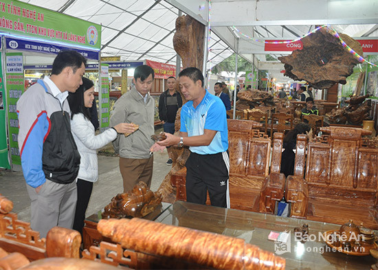 Khách hàng tham quan gian hàng sản phẩm đồ mộc mỹ nghệ của HTX TMDV làng nghề Quang Phong. Ảnh: Thu Huyền