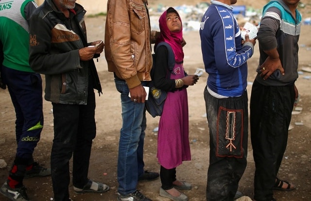 Những người dân Iraq chạy loạn xếp hàng nhận thực phẩm được phân phát miễn phí ở Tây Mosul ngày 28/3/2017. Ảnh: Reuters.