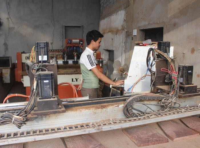 Anh Lê Văn Hào - chủ cơ sở mộc mỹ nghệ ở xã Quỳnh Hưng (Quỳnh Lưu) điều khiển máy đục gỗ vi tính. Ảnh: Việt Hùng