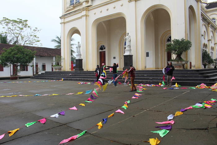 Chị em phụ nữ tranh thủ sau giờ làm việc lại tập trung treo cờ trang trí, quét dọn, làm vệ sinh môi trường xung quanh nhà thờ. Ảnh: Thái Hiền 