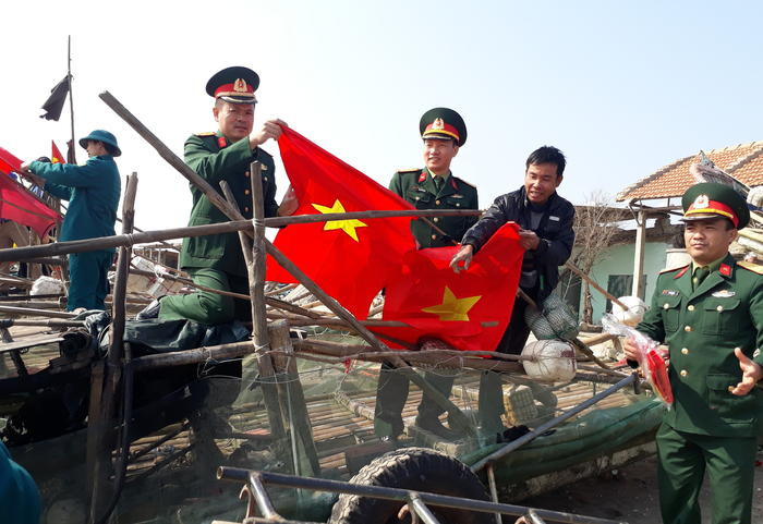 Đại diện lãnh đạo Ban CHQS Diễn Châu, Ban CHQS TP Vinh và Thành đoàn Vinh cùng ngư dân treo cờ Tổ quốc lên bè mảng. Ảnh: Mai Sao