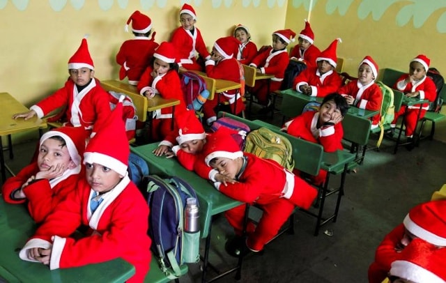 Trẻ em mặc trang phục Santa Claus ngồi trong lớp học trước khi tham gia lễ mừng Giáng sinh tại một trường học ở Chandigarh, Ấn Độ