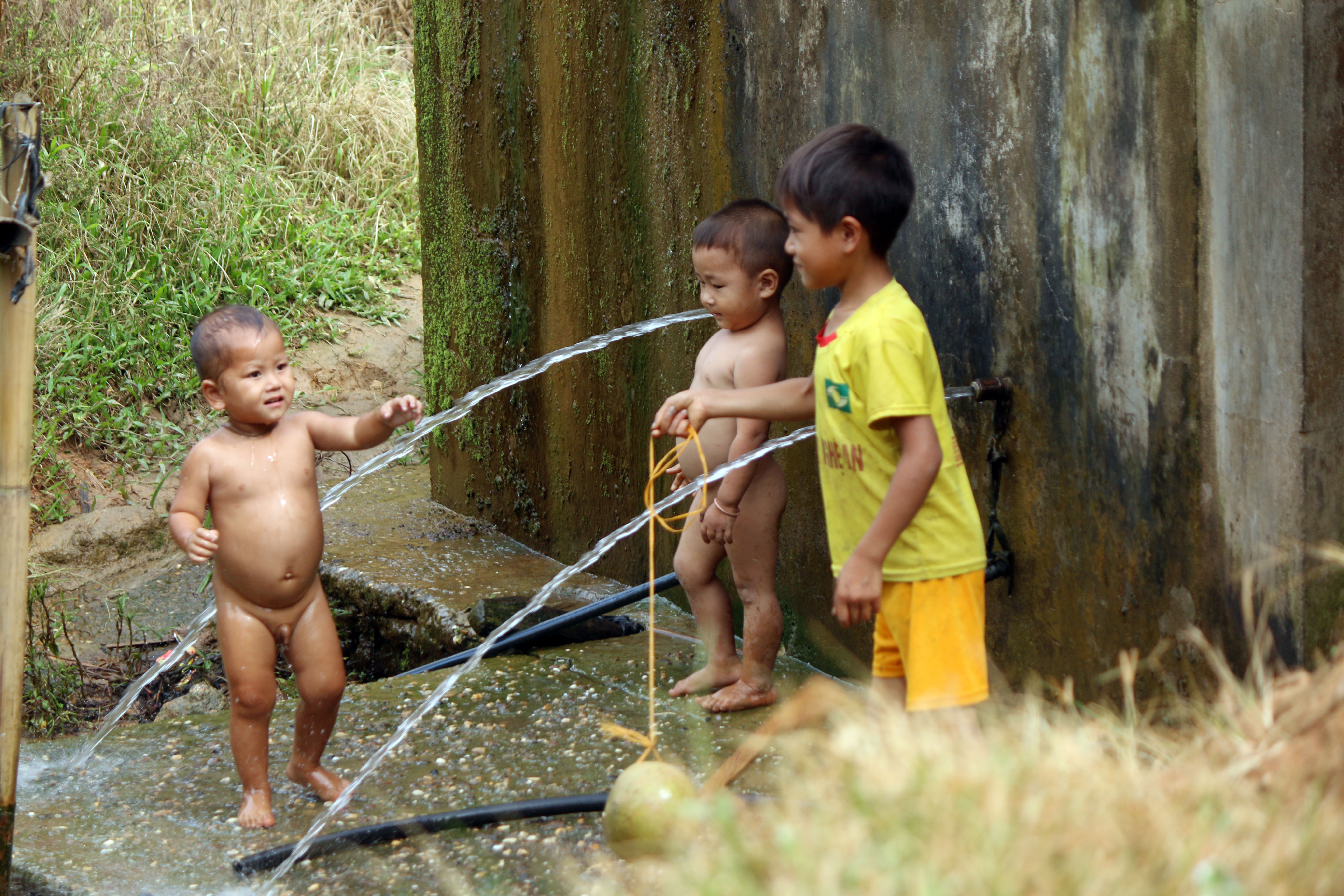 Những đứa trẻ người Mông mình trần chơi đùa bên bể nước ngày lạnh.