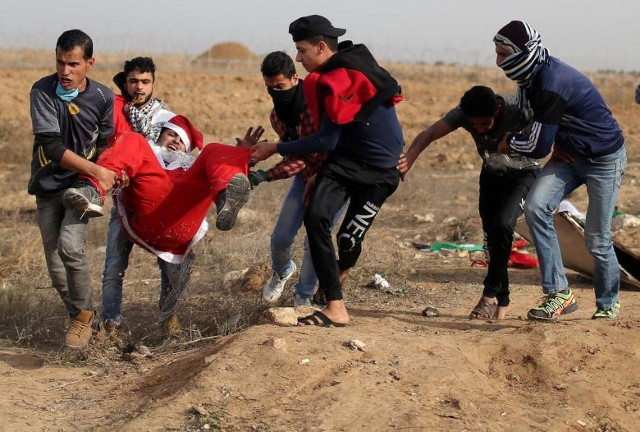 Một người biểu tình Palestine bị thương khi ăn mặc như ông già Noel được di tản trong các cuộc đụng độ với quân đội Israel, trong một cuộc biểu tình khi người Palestine gọi một 