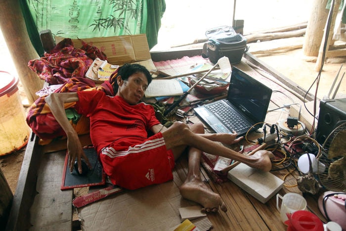 Lương Văn Thưởng nằm làm thơ bên chiếc máy tính mới. Ảnh: Đào Thọ