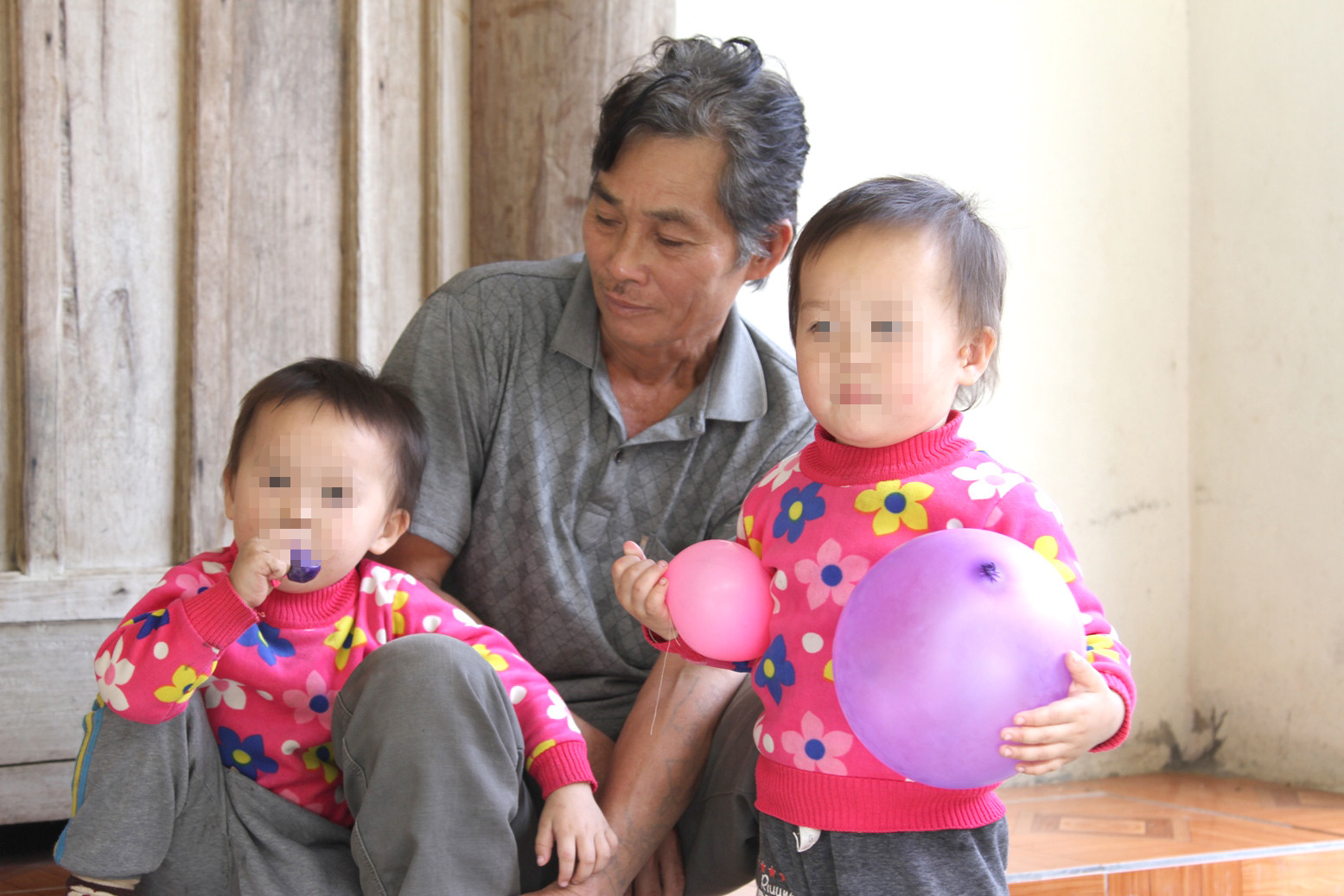 Hai đứa trẻ sinh đôi mang 2 dòng máu Việt - Trung đang nô đùa bên ông ngoại ở xã Xá Lượng (Tương Dương). Ảnh: Nhật Lân