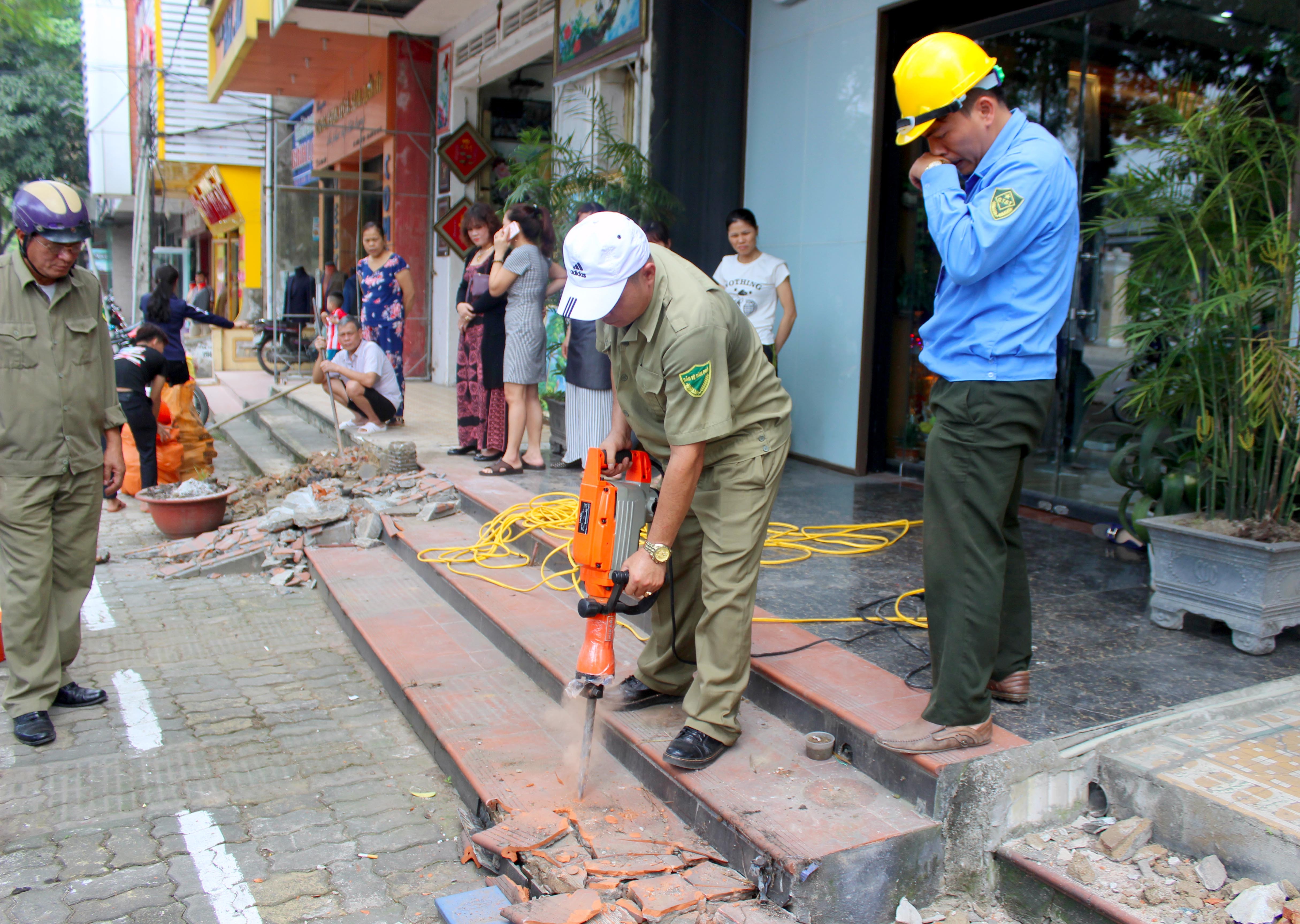 Lục lượng chức năng phá dỡ những tam cấp lấn chiếm vỉa hè trên đường Hồ Tùng Mậu. Ảnh: Quang An