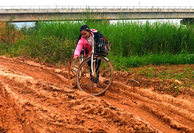 Các em học sinh hết sức vất vả đi bên chiếc cầu chậm tiến độ. Ảnh: Hồ Phương