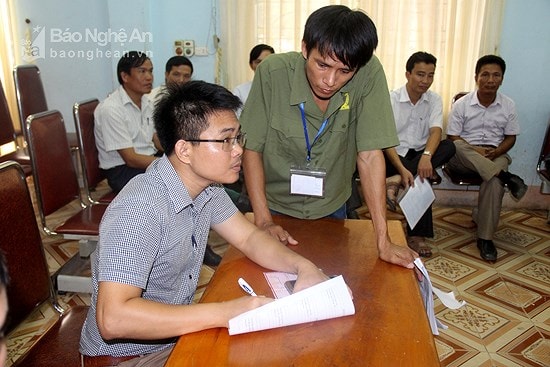 Cán bộ hướng dẫn người dân làm thủ tục đấu giá đất ở thị trấn Yên Thành. Ảnh tư liệu