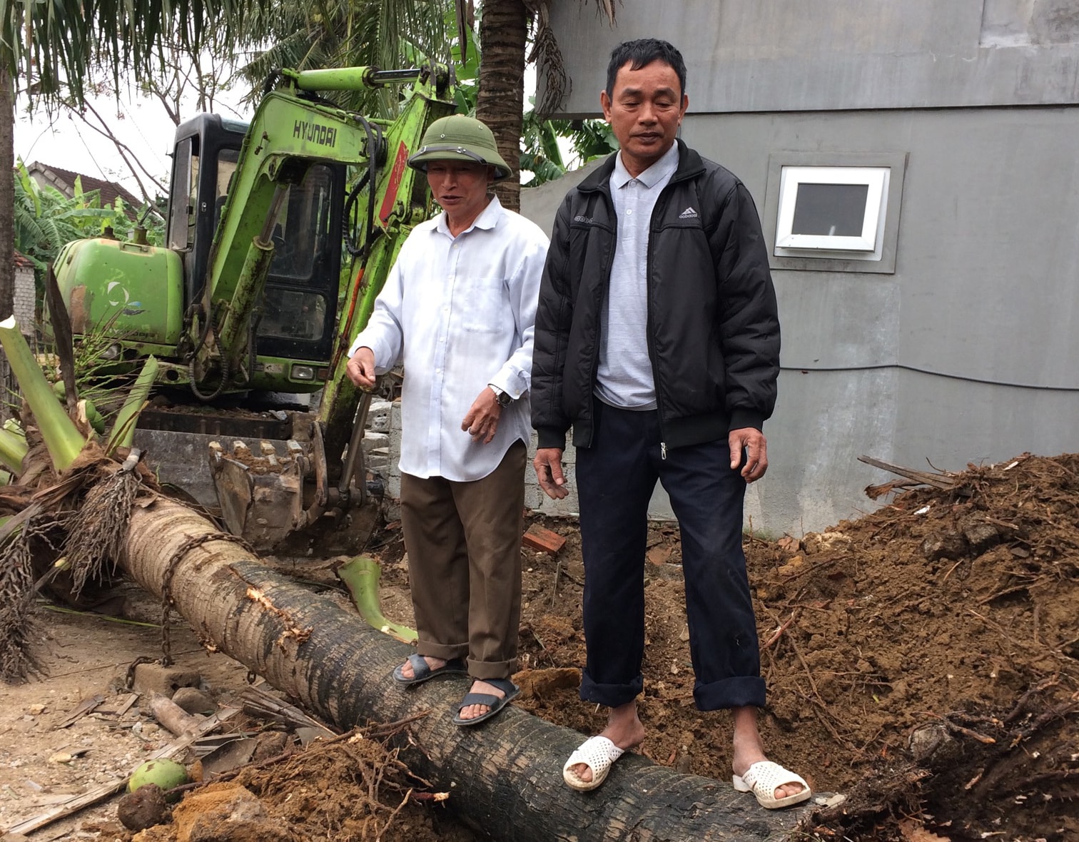 Đồng chí Hoàng Ngọc Bình- Bí thư chi bộ thôn Nghĩa Phú (áo trắng) chỉ đạo dỡ bỏ tường rào, cây xanh do người dân hiến để mở rộng đường. Ảnh: PV