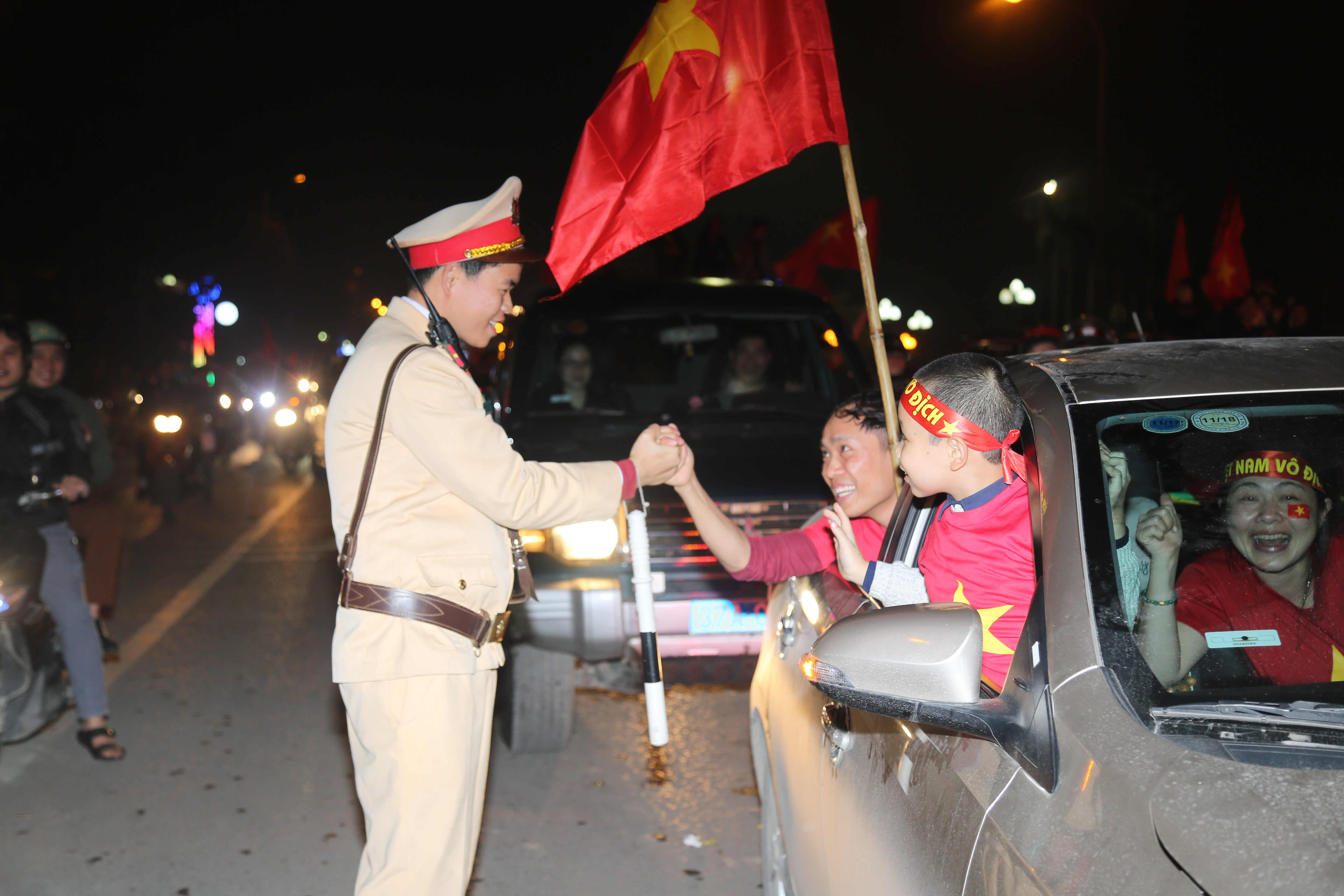 Chiến sĩ CSGT chia vui cùng người dân đang đổ ra đường ăn mừng sau chiến thắng của U23 Việt Nam.