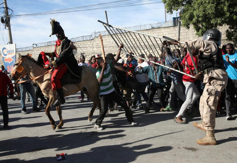 Một nhân viên Cảnh sát Quốc gia Haiti đã đánh nhau với một người biểu tình đã bắt giữ hàng rào của một hàng rào cảnh sát trong một cuộc biểu tình chống lại những lời bình luận của Tổng thống Hoa Kỳ Donald Trump về Haiti, trên các đường phố Port-au-Prince, Haiti, ngày 22 tháng 1 năm 2018. REUTERS / Andres Martinez Casares