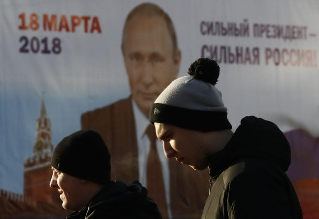 Người dân Matxcơva đi ngang bích chương vận động bầu cử của ông Putin. Ảnh: REUTERS