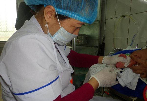 Lấy máu gót chân để sàng lọc sau sinh cho trẻ em ở huyện Diễn Châu. Ảnh: Mỹ Hà