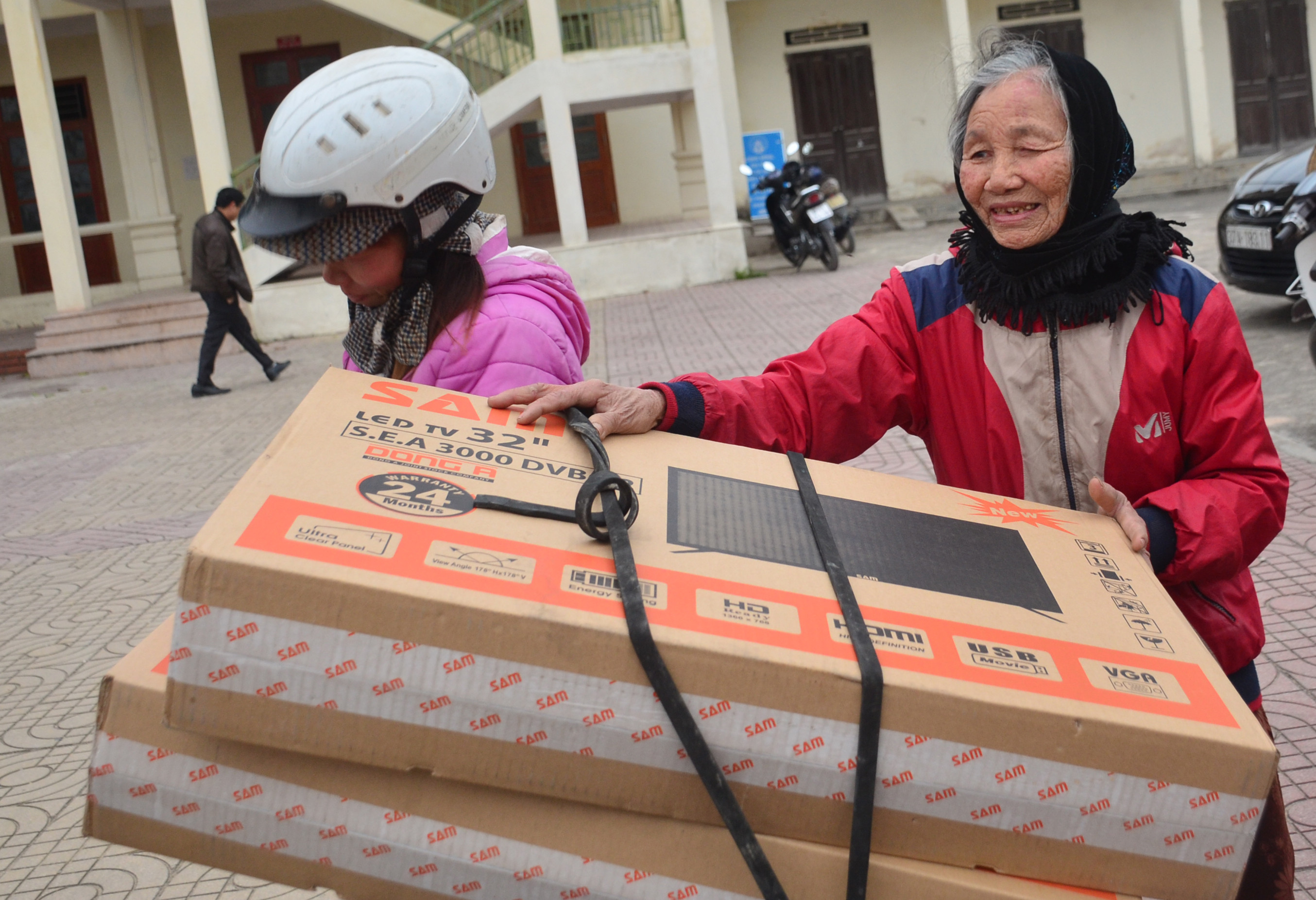 Cụ Trần Thị Xuân (80 tuổi) ở xóm 3, xã Quỳnh Lộc, thị xã Hoàng Mai vui mừng khi nhận quà tặng là chiếc tivi từ đoàn công tác của Tỉnh ủy. Ảnh: Thành Duy